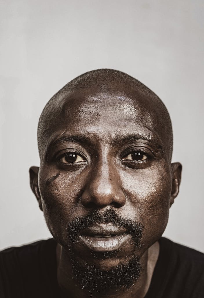 Intense close-up portrait of an African man with a serious expression and facial hair.