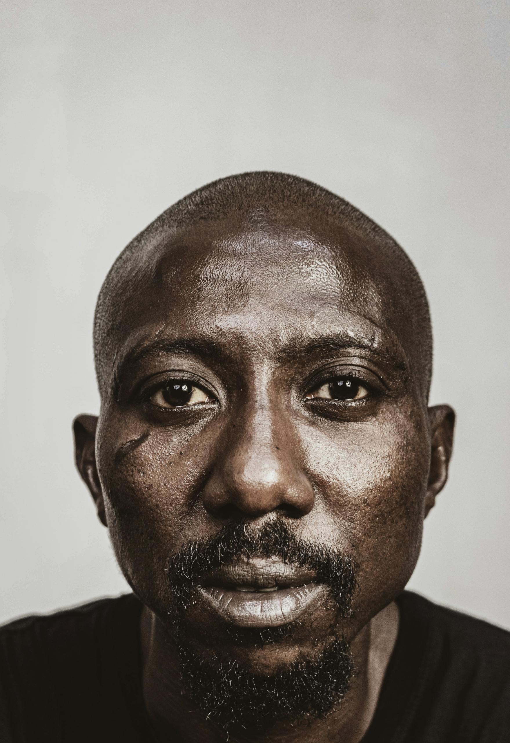 Intense close-up portrait of an African man with a serious expression and facial hair.