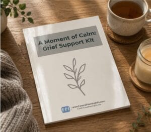 A grief support kit workbook on a wooden table beside tea, a lit candle, and a blanket during the grieving process.