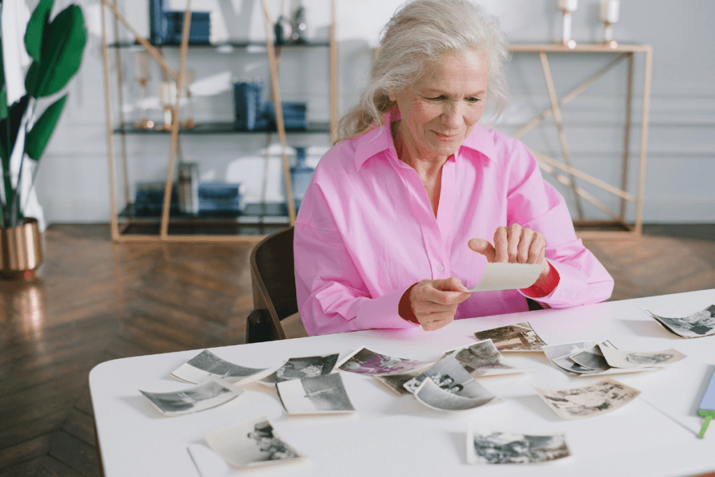 Older woman sorting through family photographs while deciding which memories she wants to preserve.