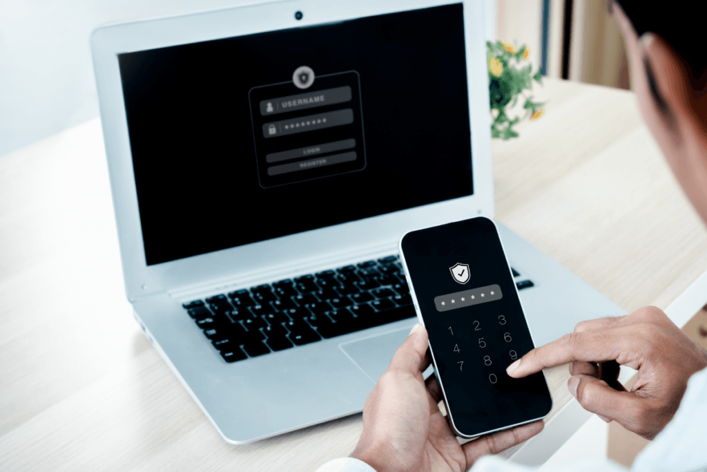 Person using a smartphone verification code while logging into an account on a laptop.