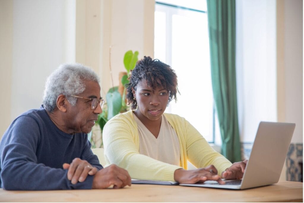 Older man and younger woman reviewing information together on a laptop at home.